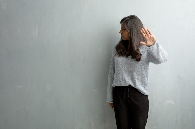 Junge indische Frau gegen eine Schmutzwand ernst und bestimmt