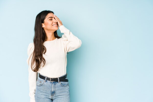 Junge indische Frau lokalisiert auf blauer Wand, die glückliche, sorglose, natürliche Emotion lacht.