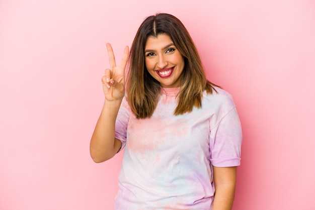 Junge indische Frau lokalisiert auf rosa Wand, die Nummer zwei mit den Fingern zeigend.