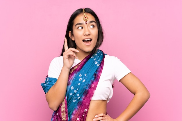 Junge indische Frau mit Sari über isoliertem Hintergrund, der eine Idee denkt, die den Finger nach oben zeigt