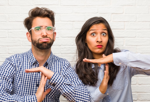 Foto junge indische frau und kaukasische mannpaare, die müde und gelangweilt sind und eine auszeitgeste machen, müssen wegen des arbeitsstresses, zeitkonzept aufhören