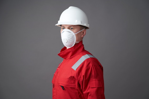 Junge Ingenieurarbeiter tragen einen Helm, Gesichtsmaske