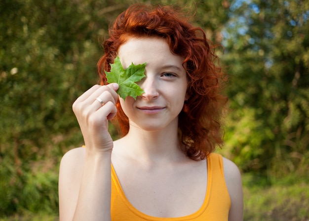 Foto junge ingwerfrau mit grünem blatt in ihrer hand