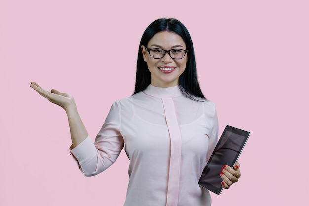 Junge, intelligente asiatische Frau mit Brille hält Tablet-PC und Werbefläche in der Hand