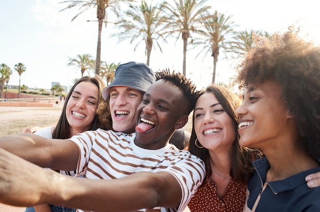 Junge interrassische Freunde machen eine Fotogruppe von Menschen, die ihre Freizeit zusammen genießen