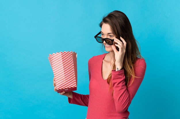 Junge irische Frau lokalisiert mit 3D-Brille und hält einen großen Eimer Popcorn