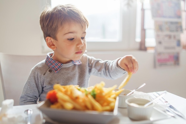 Junge isst Essen auf dem Tisch