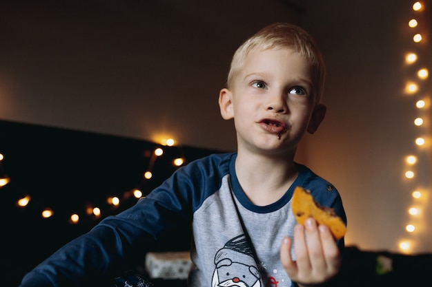 Junge isst Kekse und träumt von Geschenken zu Weihnachten