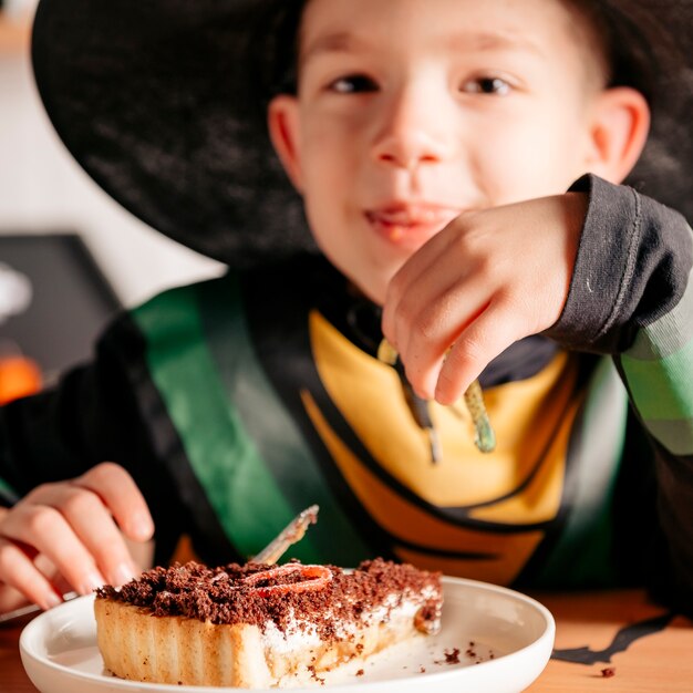 Junge isst Kuchen auf Halloween-Party