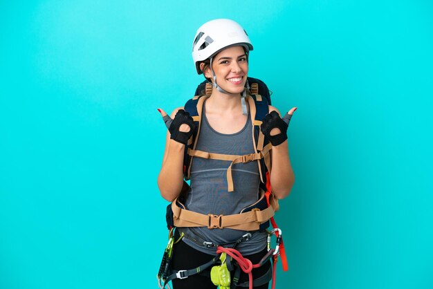 Junge italienische Kletterin isoliert auf blauem Hintergrund mit Daumen nach oben Geste und lächelnd