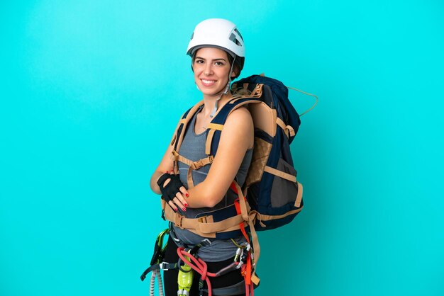 Junge italienische Kletterin isoliert auf blauem Hintergrund mit verschränkten Armen und freut sich