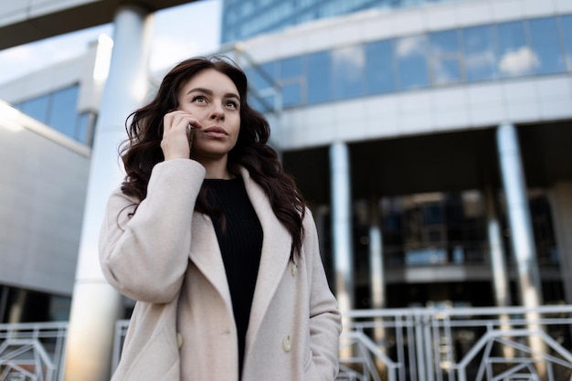 Junge Journalistin, die telefonisch anruft, während sie die Straße hinuntergeht