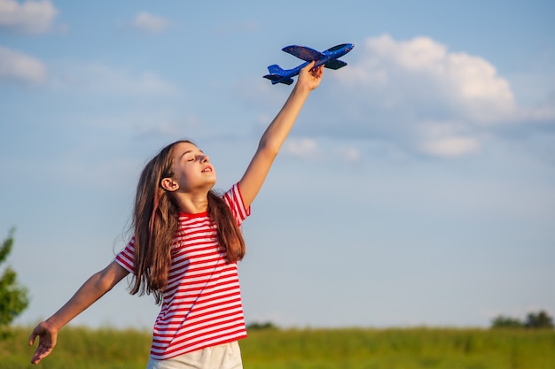 Junge Jugendliche, die ein Flugzeug hält. Traumkonzept.