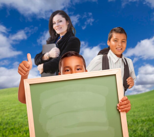 Junge Jungen mit leerer Kreidetafel Lehrer hinterher auf dem Gras