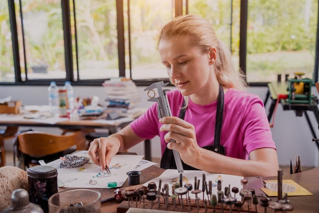 Junge Juwelierin stellt in der Werkstatt Schmuck her