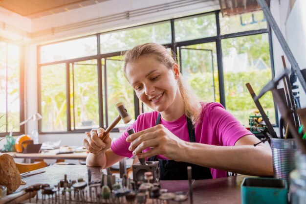 Junge Juwelierin stellt in der Werkstatt Schmuck her