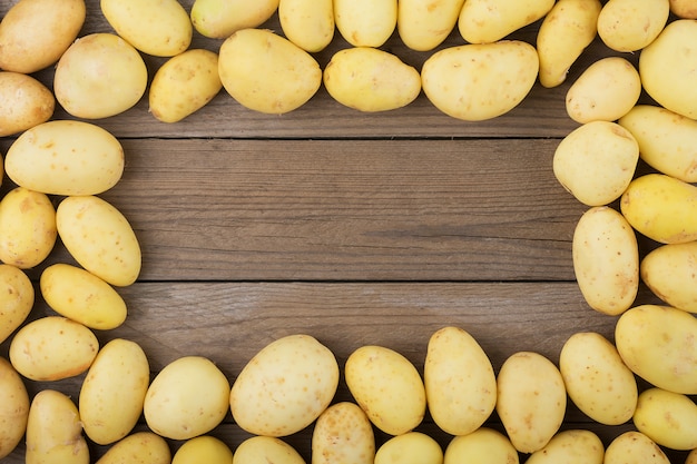 Junge Kartoffeln auf Holztisch. Rustikaler Stil. Ansicht von oben. Flach liegen.