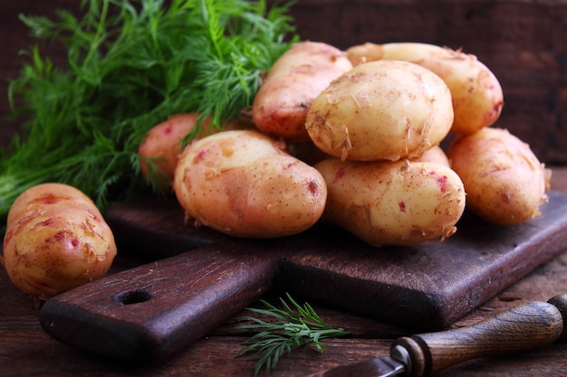 Junge Kartoffeln in einer hölzernen Platte auf einem hölzernen Hintergrund