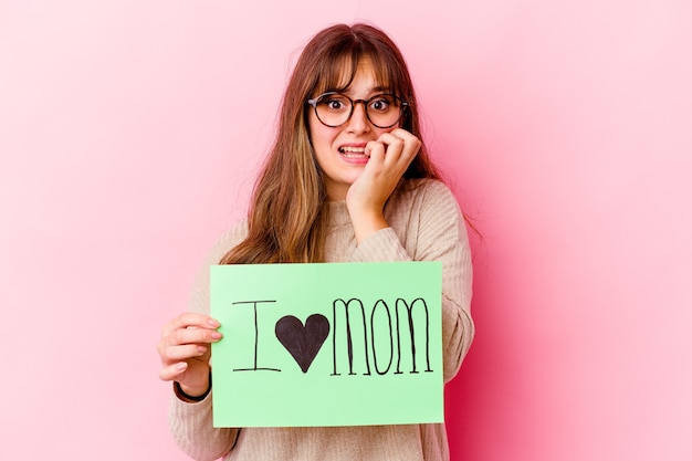 Junge Kaukasierin, die eine Ich liebe Mama hält, isoliert beißende Fingernägel, nervös und sehr ängstlich.