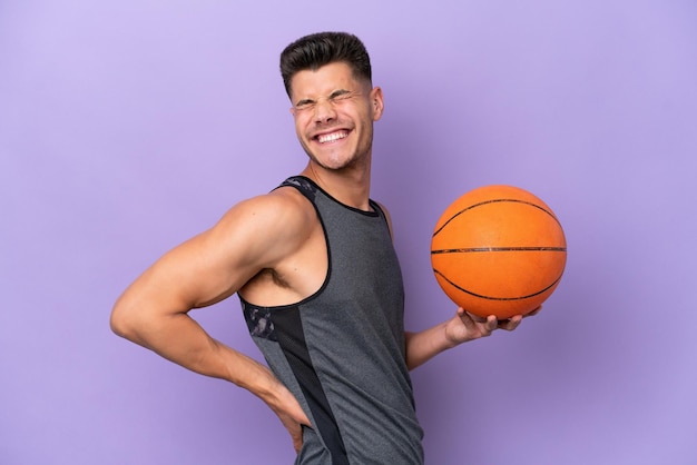 Junge kaukasische Basketballspielerin isoliert auf violettem Hintergrund, die unter Rückenschmerzen leidet, weil sie sich Mühe gegeben hat
