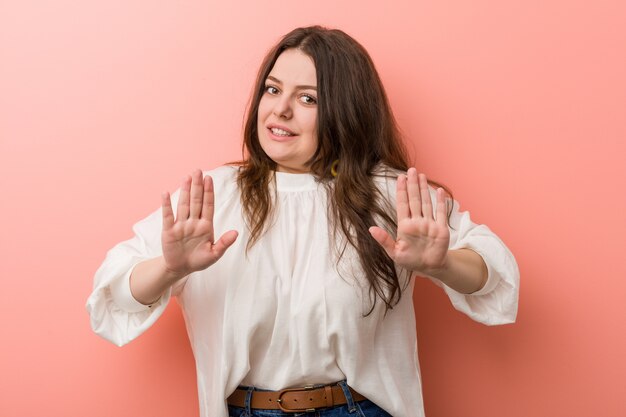 Junge kaukasische curvy Frau, die gegen Rosa steht