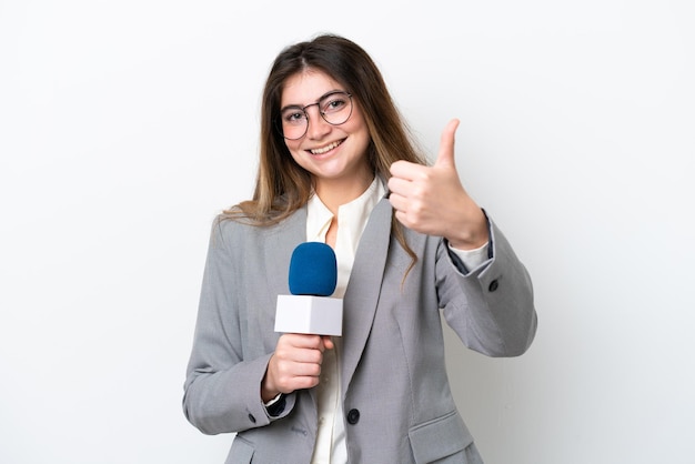 Junge kaukasische Fernsehmoderatorin isoliert auf weißem Hintergrund mit Daumen nach oben, weil etwas Gutes passiert ist