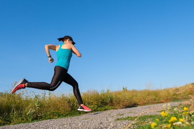 Junge kaukasische Fitnessfrau läuft die Landstraße hinauf