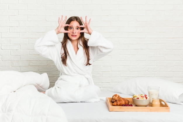 Junge kaukasische Frau auf dem Bett, die Augen offen hält, um eine Erfolgschance zu finden.