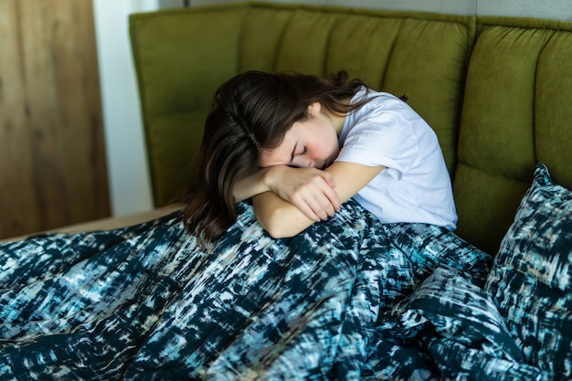 Junge kaukasische Frau auf dem Bett mit Schlaflosigkeit oder Depression