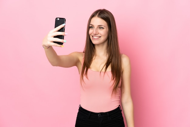 Junge kaukasische Frau auf rosa Wand, die ein selfie macht