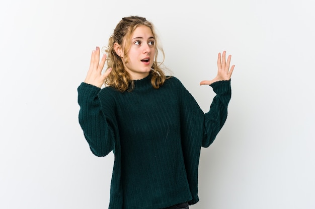 Junge kaukasische Frau auf weißer Wand, die zum Himmel schreit und aufschaut, frustriert.