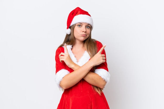 Foto junge kaukasische frau, die als mama noel verkleidet ist, isoliert auf weißem hintergrund, die auf die seitenteile zeigt, die zweifel haben