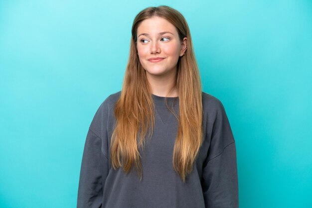 Junge kaukasische Frau, die auf blauem Hintergrund isoliert ist, macht Zweifel, Geste, die Seite suchen