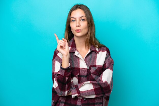 Junge kaukasische Frau, die auf blauem Hintergrund isoliert ist und beabsichtigt, die Lösung zu realisieren, während sie einen Finger hochhebt