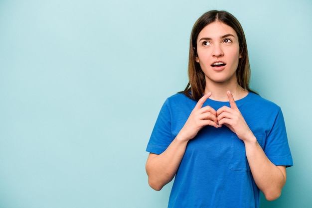 Junge kaukasische Frau, die auf blauem Hintergrund isoliert ist und einen Plan im Kopf hat, der eine Idee aufstellt