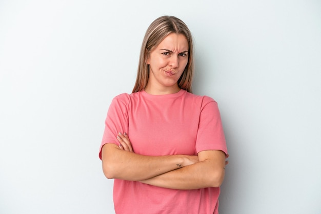 Junge kaukasische Frau, die auf blauem Hintergrund lokalisiert wird, runzelt das Gesicht in Unmut, hält die Arme verschränkt.