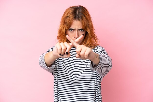 Foto junge kaukasische frau, die auf rosa hintergrund isoliert ist und mit der hand eine stop-geste macht, um eine aktion zu beenden