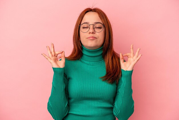 Junge kaukasische Frau, die auf rosafarbenem Hintergrund isoliert ist, entspannt sich nach einem harten Arbeitstag, sie macht Yoga.