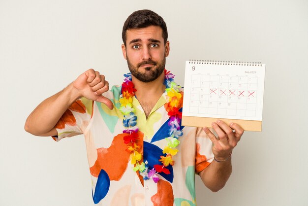 Junge kaukasische Frau, die auf seine Ferien wartet, hält einen Kalender lokalisiert auf weißer Wand, die eine Abneigungsgeste zeigt, Daumen nach unten