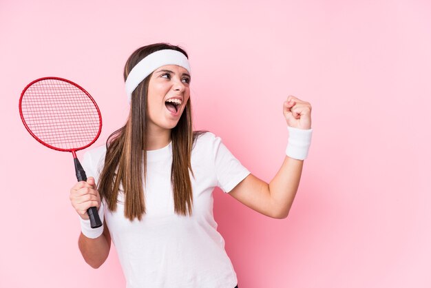 Junge kaukasische Frau, die Badminton spielt, isolierte das Erhöhen der Faust nach einem Sieg, Gewinnerkonzept.