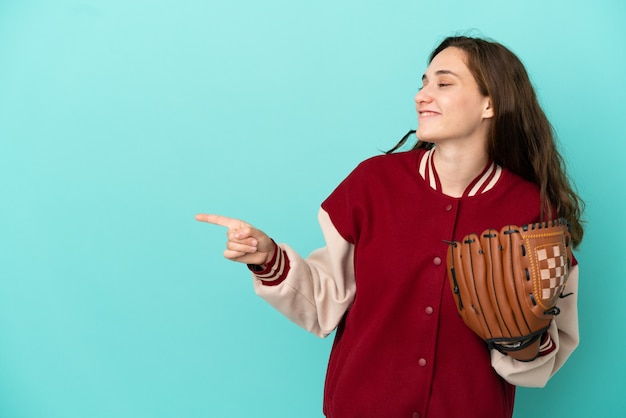 Junge kaukasische Frau, die Baseball spielt, isoliert auf blauem Hintergrund, zeigt mit dem Finger zur Seite und präsentiert ein Produkt