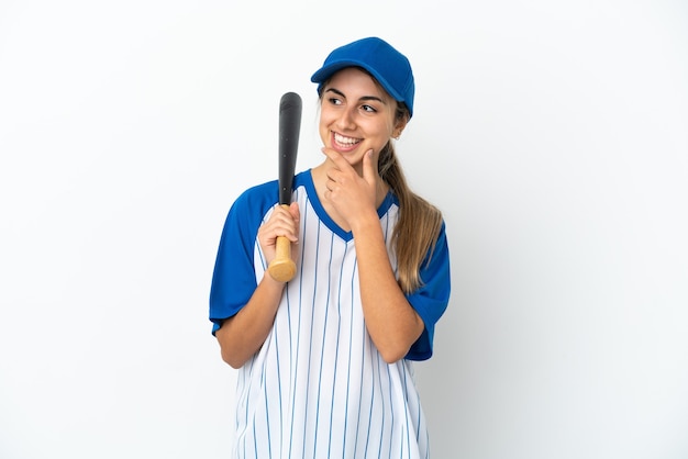 Junge kaukasische Frau, die Baseball spielt, isoliert auf weißem Hintergrund, der zur Seite schaut und lächelt