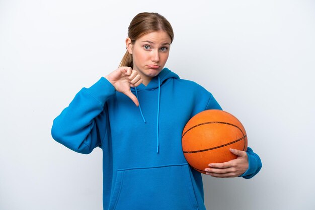 Junge kaukasische Frau, die Basketball spielt, isoliert auf weißem Hintergrund, zeigt Daumen nach unten mit negativem Ausdruck