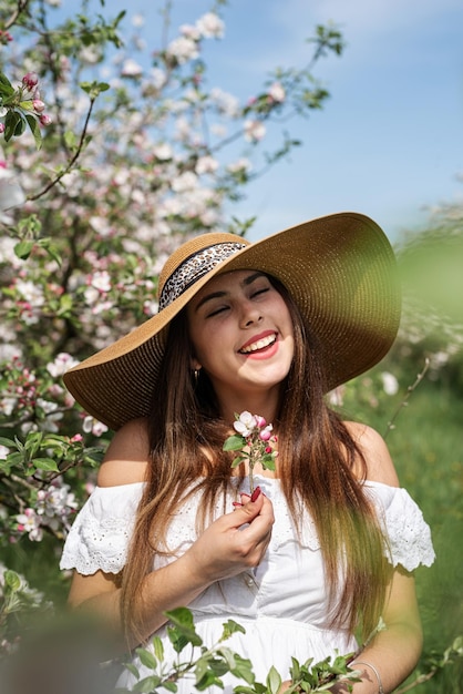 Junge kaukasische Frau, die die Blüte eines Apfelbaums genießt