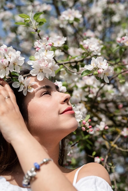 Junge kaukasische Frau, die die Blüte eines Apfelbaums genießt