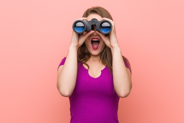 Junge kaukasische Frau, die durch Fernglas schaut