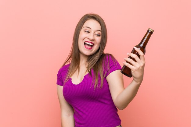 Junge kaukasische Frau, die eine Bierflasche hält