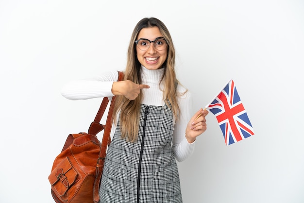 Junge kaukasische Frau, die eine britische Flagge lokalisiert auf weißem Hintergrund mit Überraschungsgesichtsausdruck hält