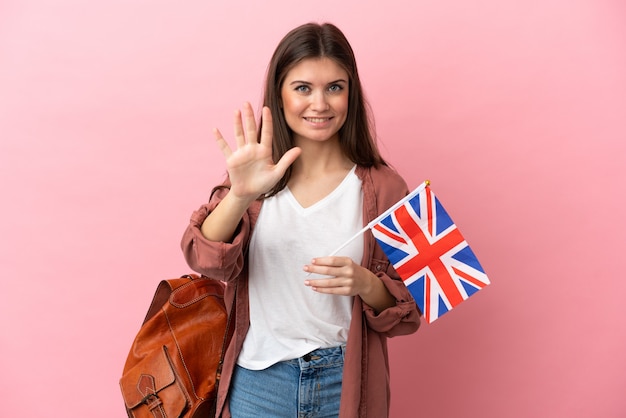 Junge kaukasische Frau, die eine Flagge des Vereinigten Königreichs hält, die isoliert fünf mit den Fingern zählt