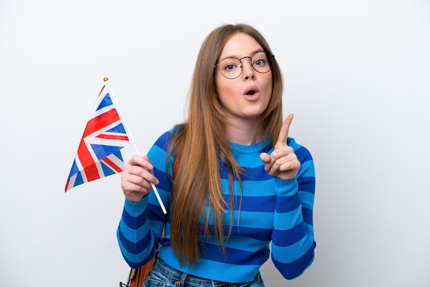 Junge kaukasische Frau, die eine Flagge des Vereinigten Königreichs lokalisiert auf weißem Hintergrund hält